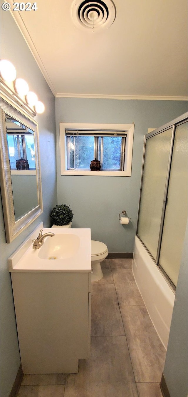 full bathroom featuring combined bath / shower with glass door, tile patterned floors, vanity, crown molding, and toilet