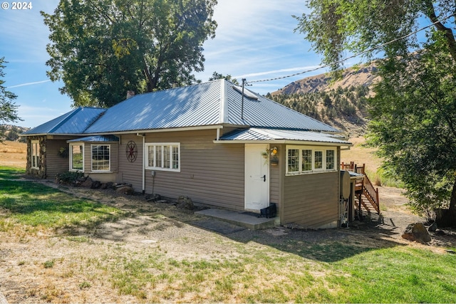 back of property featuring a mountain view and a lawn