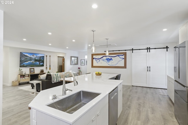 kitchen with pendant lighting, white cabinets, sink, and a barn door