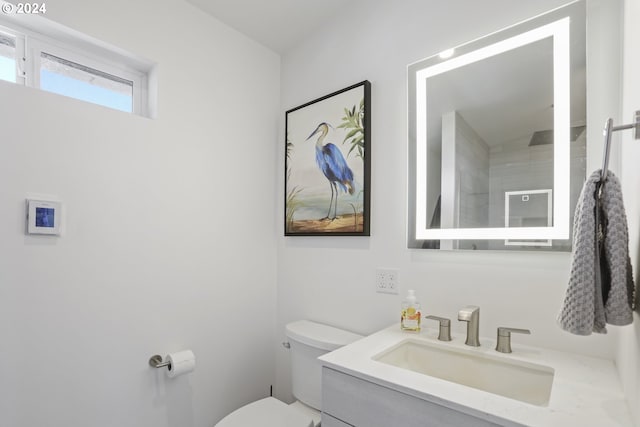 bathroom featuring a tile shower, vanity, and toilet