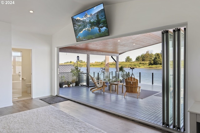 interior space featuring wood-type flooring, a water view, and vaulted ceiling