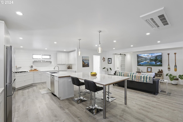 kitchen with white cabinetry, a barn door, a center island, decorative light fixtures, and sink