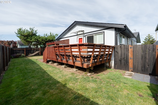 rear view of property featuring a deck and a yard