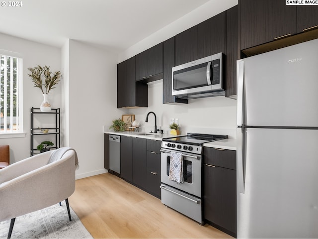 10985 E Burnside St Unit 19, Portland, OR 97216 - kitchen featuring appliances with stainless steel finishes, light countertops, light wood-style flooring, a sink, and dark cabinets
