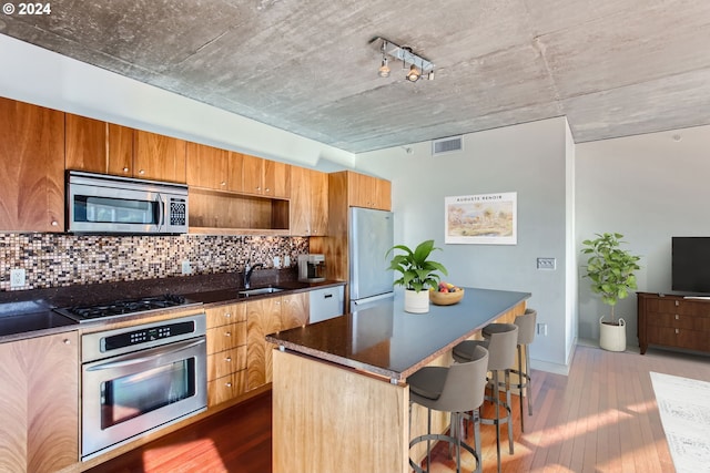 kitchen with stainless steel appliances, a breakfast bar area, decorative backsplash, a kitchen island, and dark hardwood / wood-style flooring