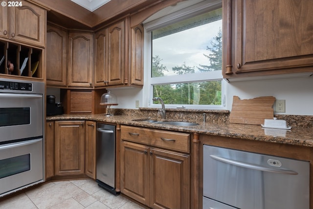 kitchen featuring sink, dark stone counters, appliances with stainless steel finishes, and light tile patterned floors