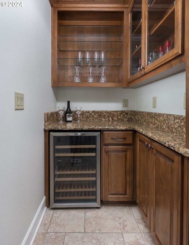 bar with light tile patterned flooring, beverage cooler, and dark stone counters