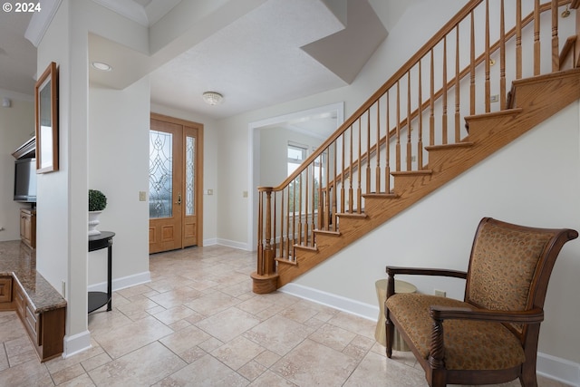 foyer entrance with stairway and baseboards