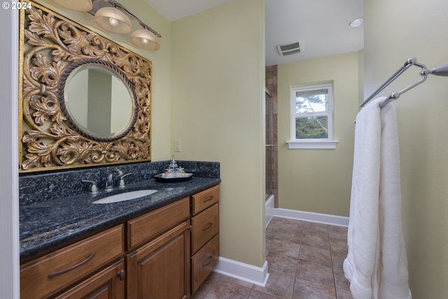 bathroom with bath / shower combo with glass door, vanity, and tile patterned floors