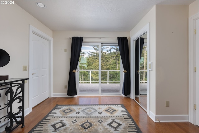 doorway featuring a textured ceiling, baseboards, and wood finished floors