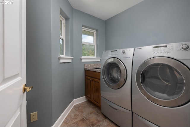 clothes washing area with baseboards, cabinet space, and washing machine and clothes dryer