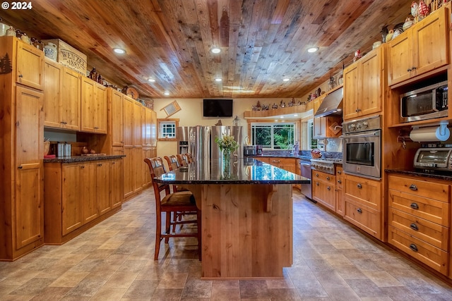 kitchen with wooden ceiling, appliances with stainless steel finishes, a kitchen bar, light tile floors, and a kitchen island