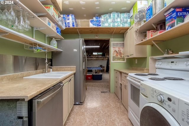 kitchen with cream cabinetry, appliances with stainless steel finishes, sink, and light tile flooring