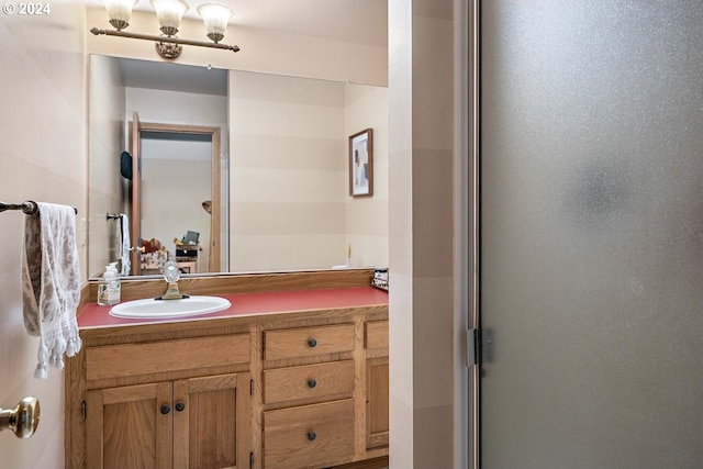 bathroom featuring a shower with shower door and vanity