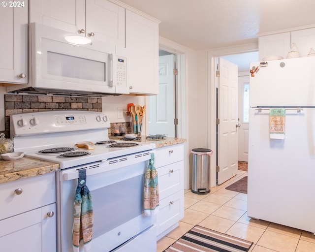 kitchen with light stone counters, white cabinets, white appliances, and light tile floors