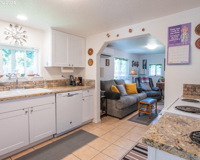 kitchen featuring a wall mounted AC, white dishwasher, light tile floors, sink, and white cabinets