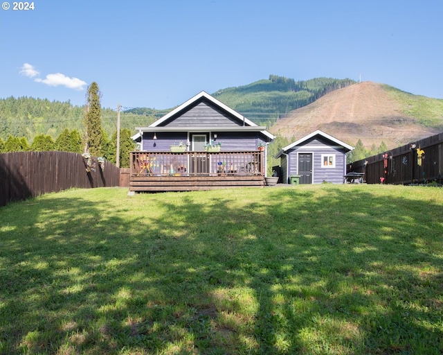 view of front of property featuring an outdoor structure, a front yard, and a deck with mountain view