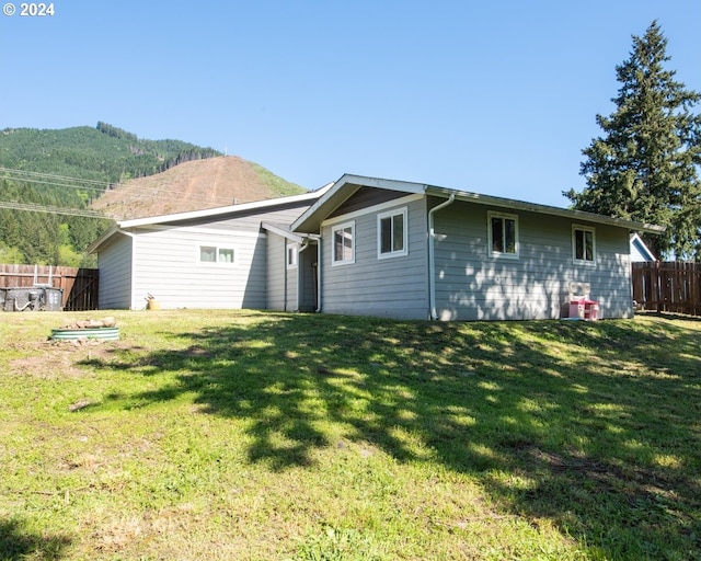 back of property featuring a mountain view and a lawn