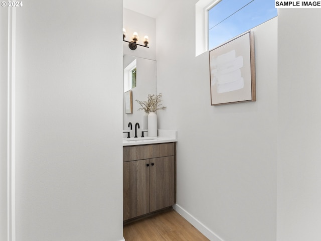 6905 N Bank St, Portland, OR 97203 - bathroom with wood finished floors, vanity, plenty of natural light, and baseboards