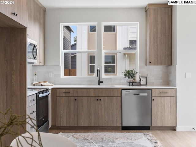 6905 N Bank St, Portland, OR 97203 - kitchen featuring appliances with stainless steel finishes, a sink, light countertops, backsplash, and light wood finished floors