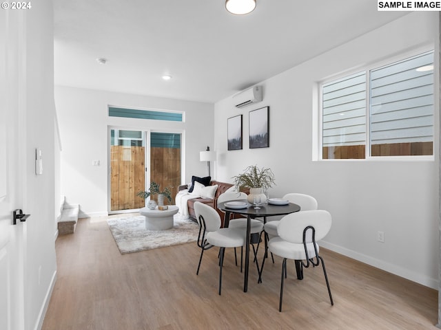 dining room with light wood-type flooring and a wall unit AC