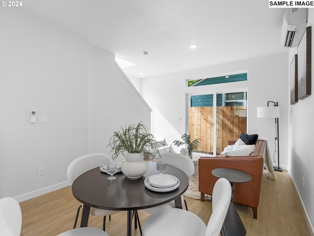 dining room with light hardwood / wood-style flooring and a wall mounted AC