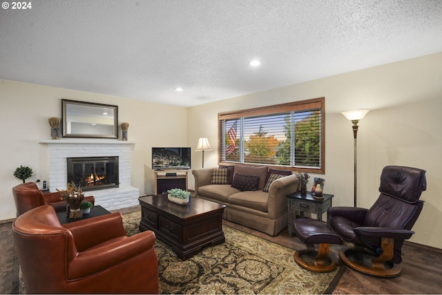 living room featuring hardwood / wood-style floors, a textured ceiling, and a fireplace