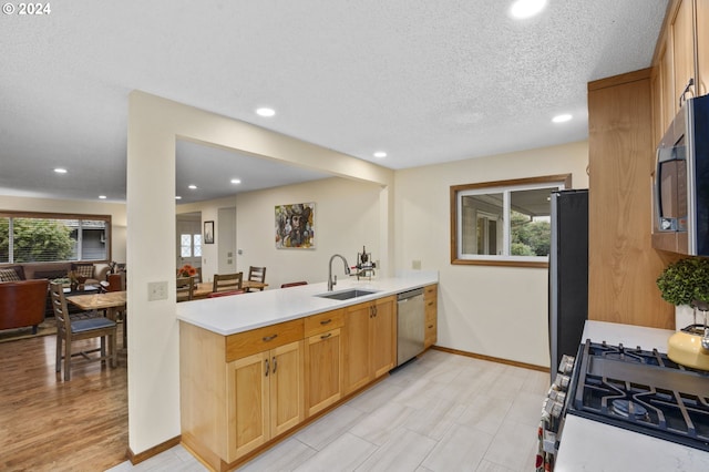 kitchen featuring kitchen peninsula, stainless steel appliances, sink, a textured ceiling, and light hardwood / wood-style floors