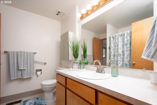 bathroom featuring toilet, vanity, and tile patterned flooring