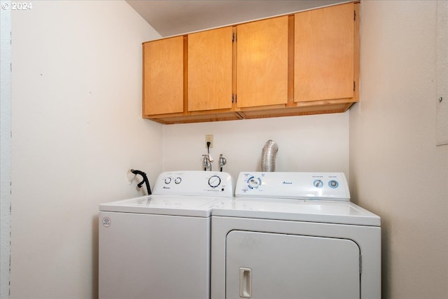 clothes washing area featuring independent washer and dryer and cabinets