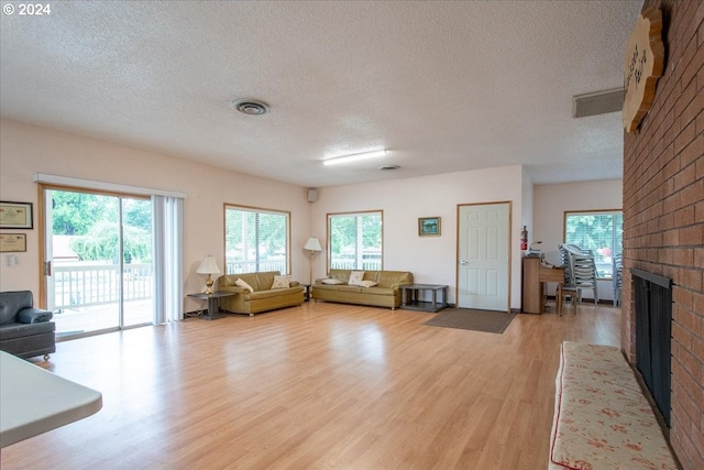 unfurnished living room with light hardwood / wood-style flooring, a healthy amount of sunlight, and a brick fireplace