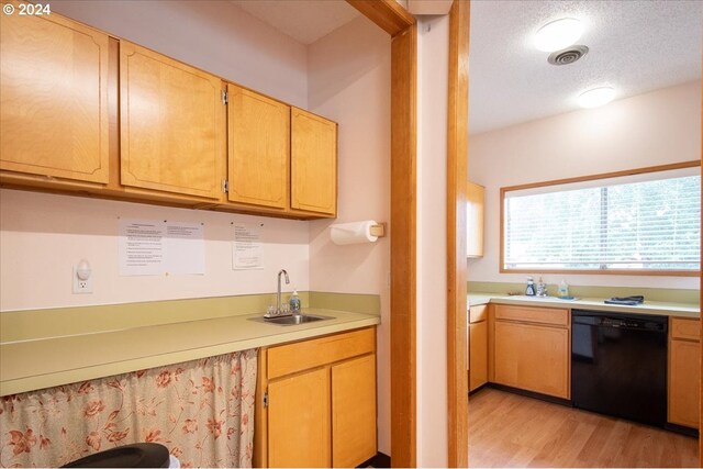 kitchen featuring black dishwasher, sink, light hardwood / wood-style flooring, and a textured ceiling