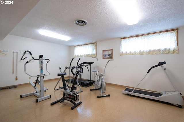 workout area with a textured ceiling, tile patterned flooring, and a healthy amount of sunlight