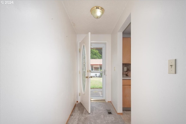 doorway to outside featuring light tile patterned flooring and a textured ceiling