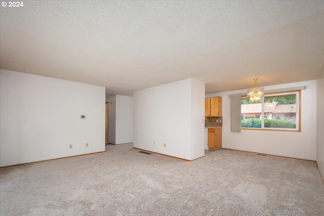 carpeted spare room featuring a chandelier and a textured ceiling