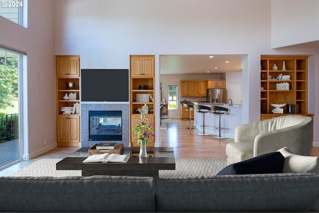 dining area with a tiled fireplace, light wood-style flooring, and baseboards