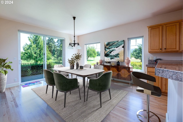 kitchen featuring light wood finished floors, light brown cabinetry, under cabinet range hood, a sink, and appliances with stainless steel finishes