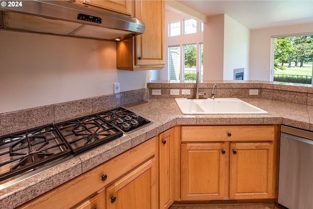 kitchen featuring stainless steel appliances, light wood-style flooring, tile countertops, and hanging light fixtures