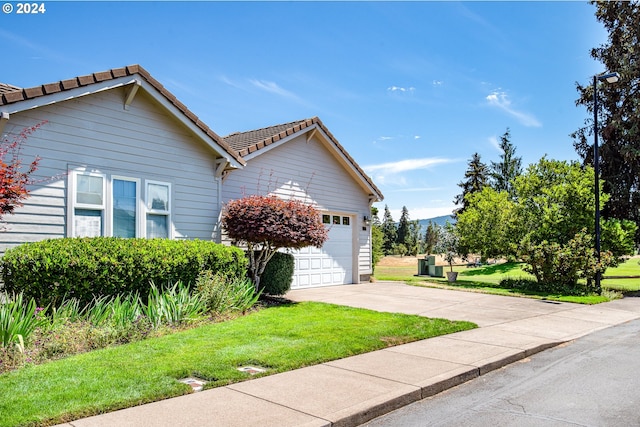 view of front of house featuring a garage, a tile roof, a front lawn, and concrete driveway