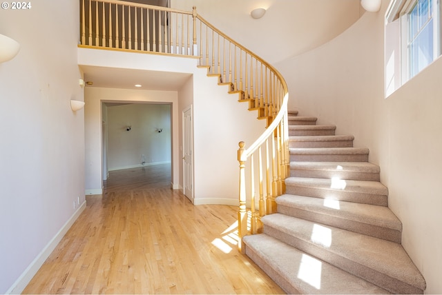 entrance foyer featuring baseboards, a towering ceiling, recessed lighting, wood finished floors, and stairway