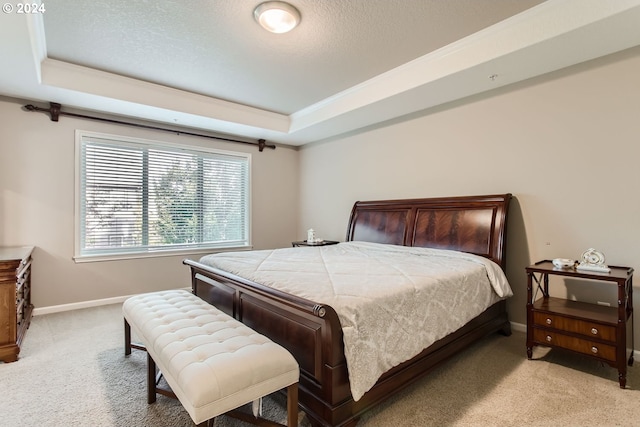 bedroom featuring a textured ceiling, light carpet, baseboards, a raised ceiling, and crown molding