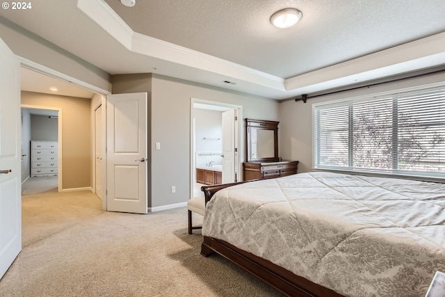 bedroom featuring a tray ceiling, crown molding, ensuite bathroom, and light carpet