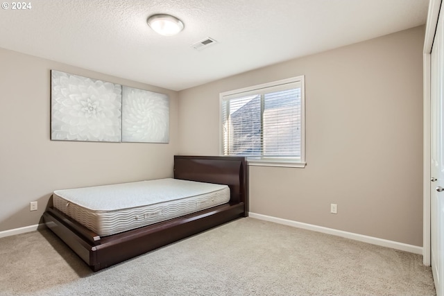 bedroom featuring baseboards, visible vents, a textured ceiling, and light colored carpet