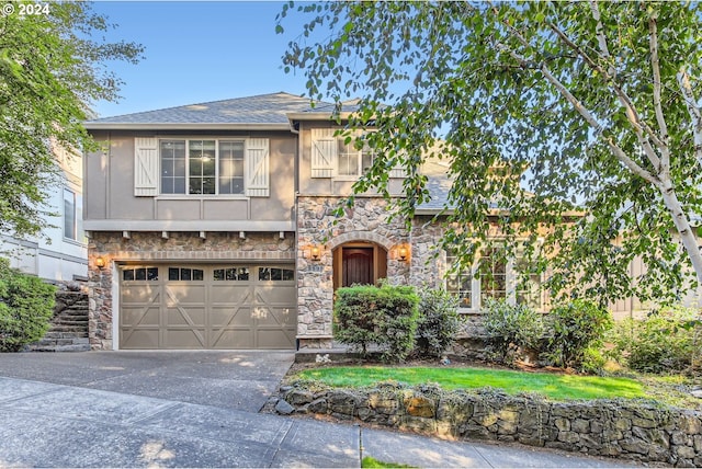 view of front of house featuring stucco siding, a shingled roof, an attached garage, stone siding, and driveway