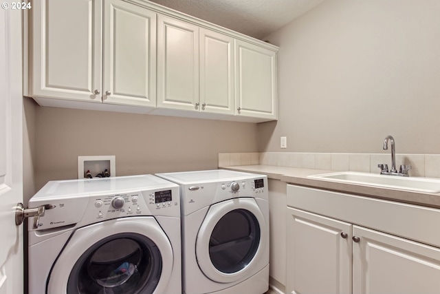 washroom with a sink, cabinet space, and washer and dryer