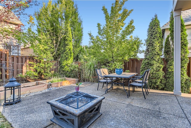 view of patio / terrace with a garden, outdoor dining area, a fenced backyard, and a fire pit