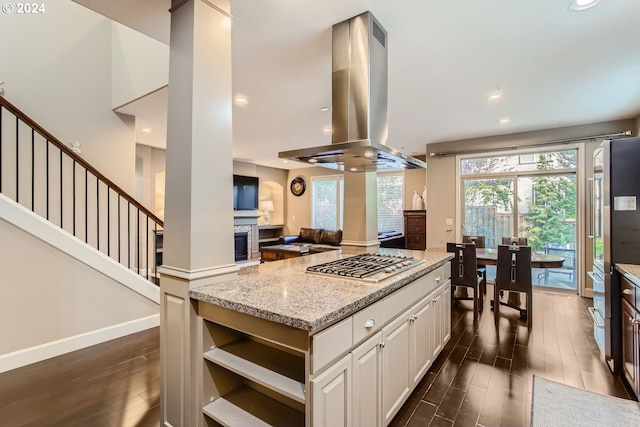 kitchen with white cabinets, appliances with stainless steel finishes, light stone countertops, dark hardwood / wood-style floors, and island range hood