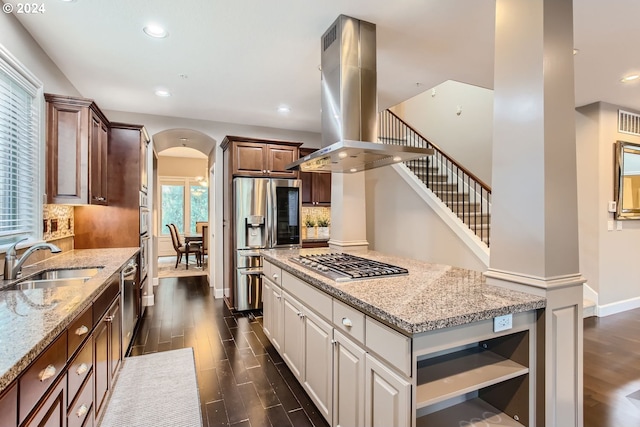 kitchen with island range hood, light stone counters, sink, dark hardwood / wood-style floors, and appliances with stainless steel finishes