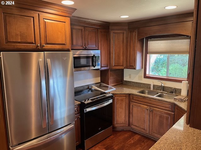 kitchen with stainless steel appliances, dark hardwood / wood-style flooring, sink, and light stone counters