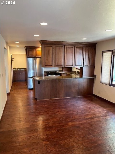 kitchen featuring stainless steel refrigerator, dark hardwood / wood-style flooring, and kitchen peninsula